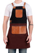 A man wearing a black and dark brown apron with tan leather accents over a white t-shirt and blue jeans, shown from the neck down against a white background.