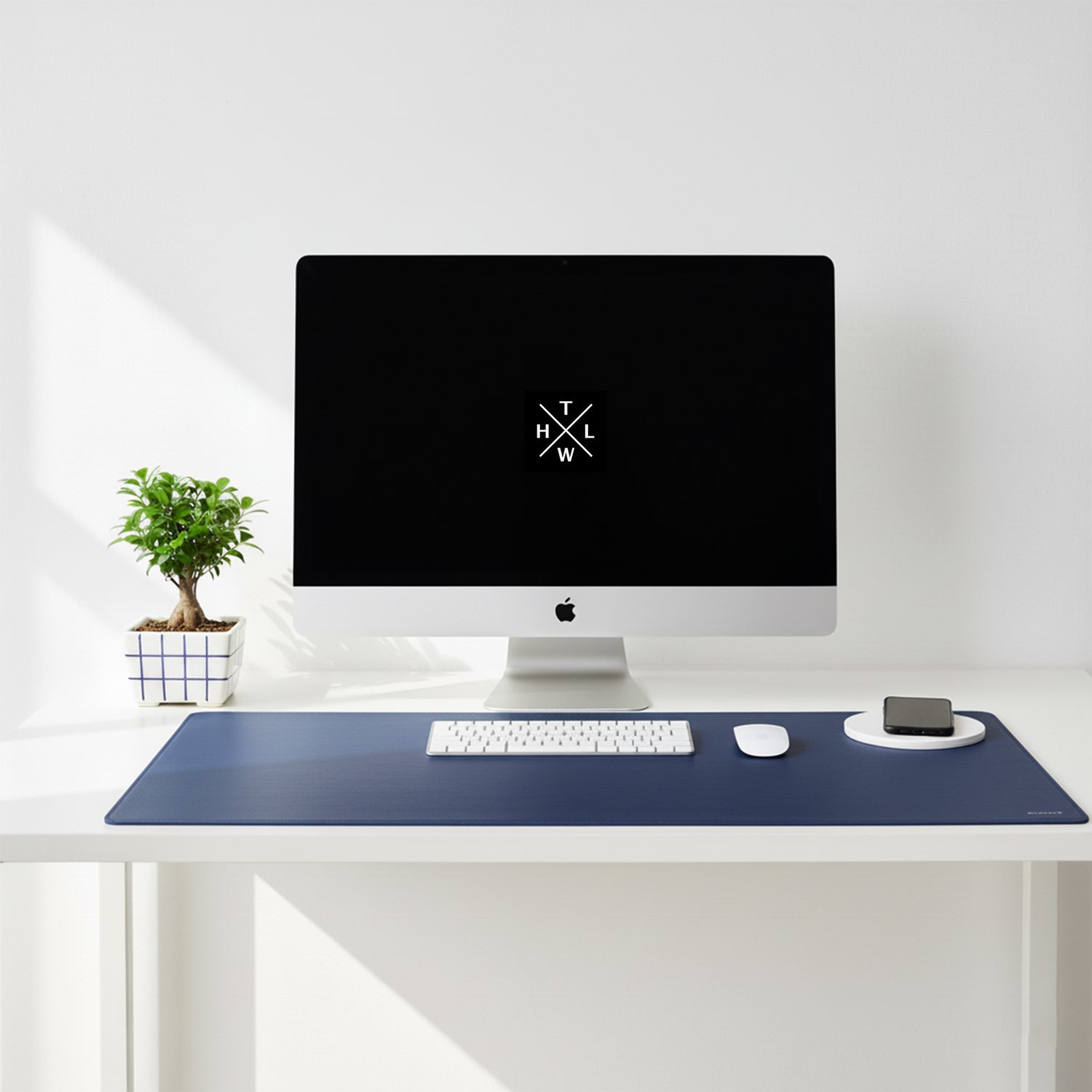 Modern desk setup with a computer monitor, keyboard, mouse, and desk pad on a white surface.