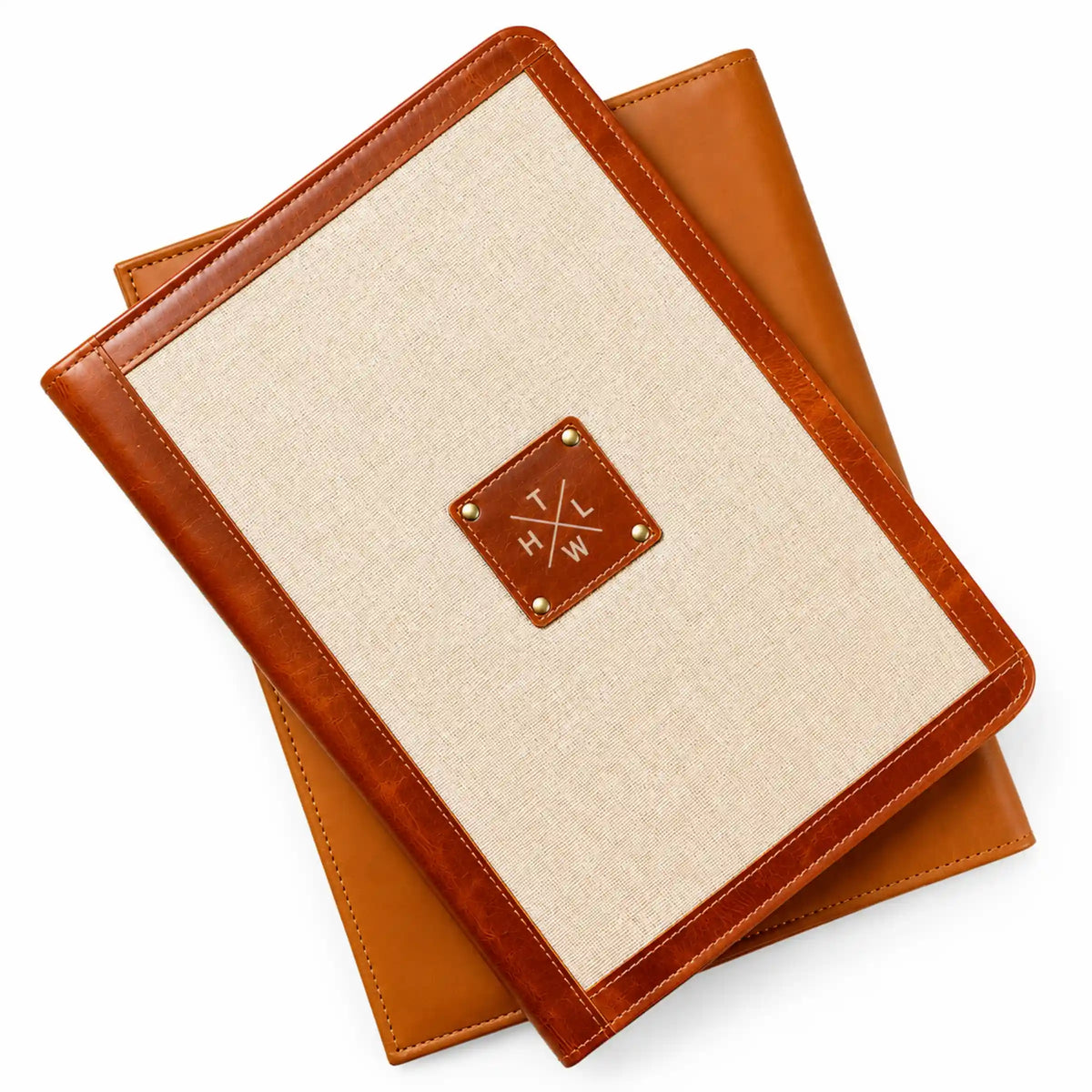 Beige canvas folder with brown leather trim, stitched edges, and a decorative leather logo patch