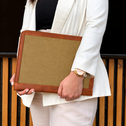 Woman holding a brown leather and canvas folder with a tan fabric panel and leather trim