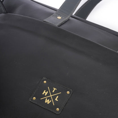 Black tote bag with gold logo and text on a white background