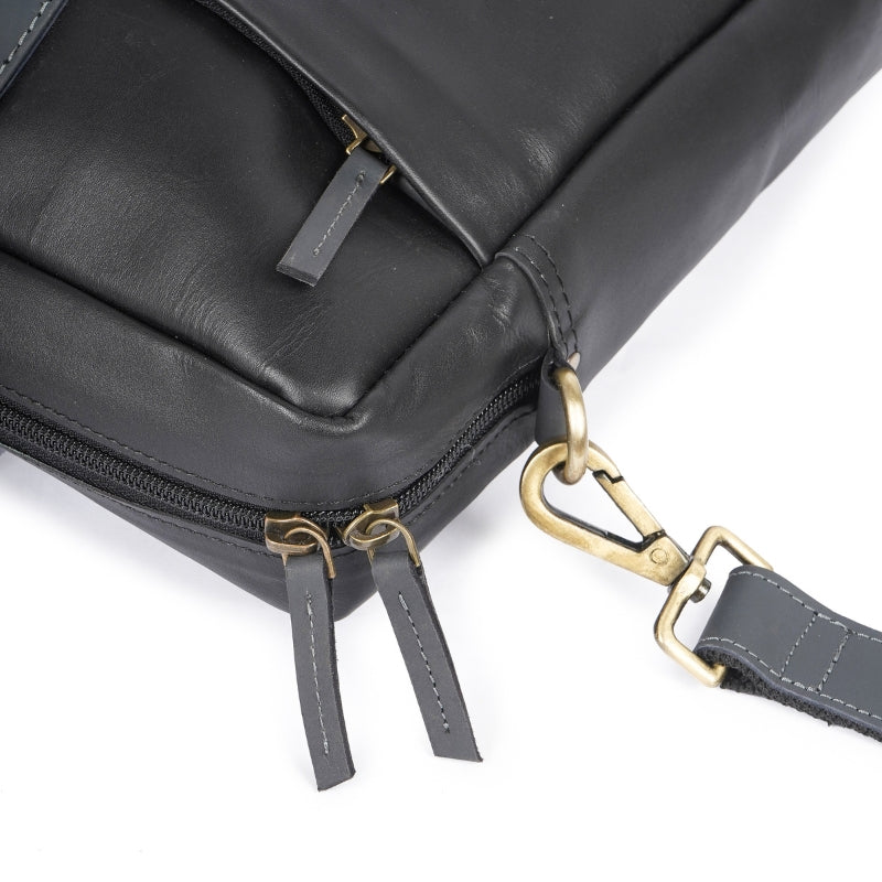 Close-up of a black leather bag with gold hardware on a white background