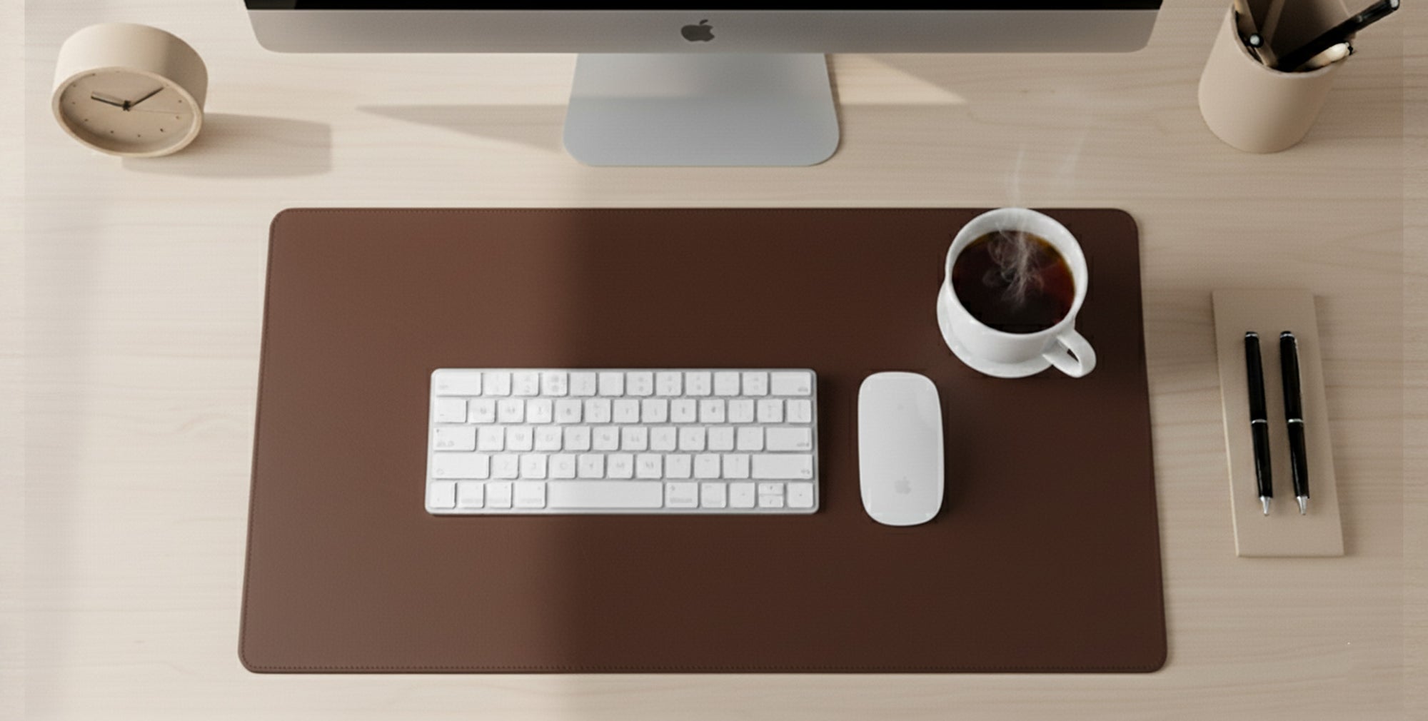 Desk setup with a computer monitor, keyboard, mouse, and coffee cup on a large brown mat.