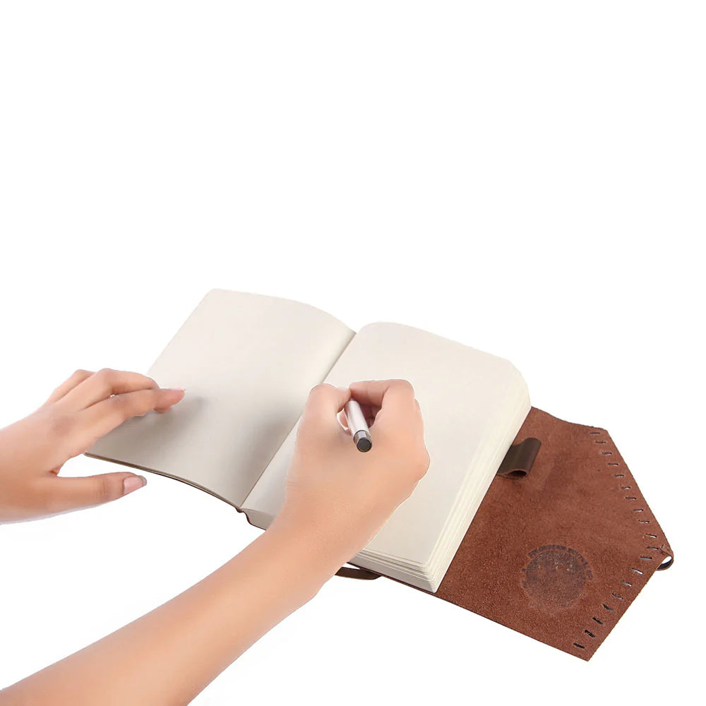 Person writing in a notebook with a brown leather cover on a white background