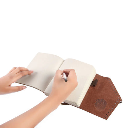 Person writing in a notebook with a brown leather cover on a white background