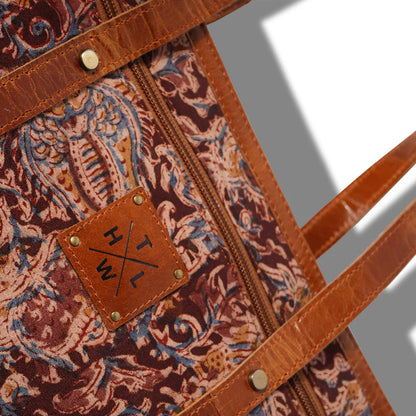 Patterned bag with leather strap and visible brand logo on a gray background