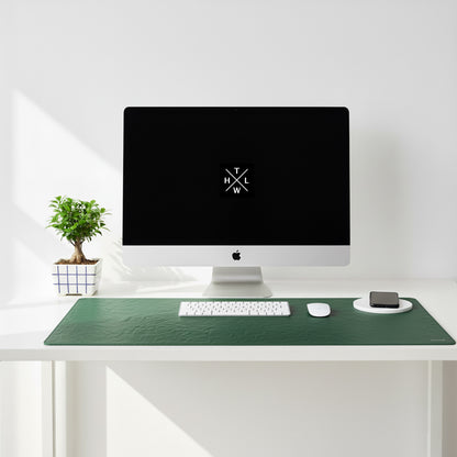 Modern desk setup with a computer monitor, keyboard, mouse, and phone on a green desk pad.
