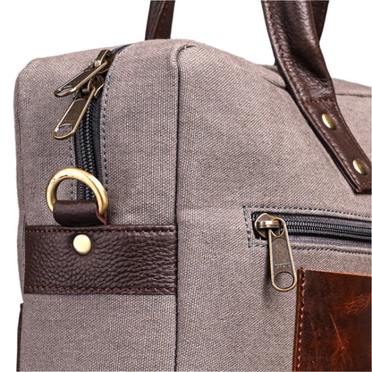Close-up of a gray bag with brown leather accents and gold zippers.