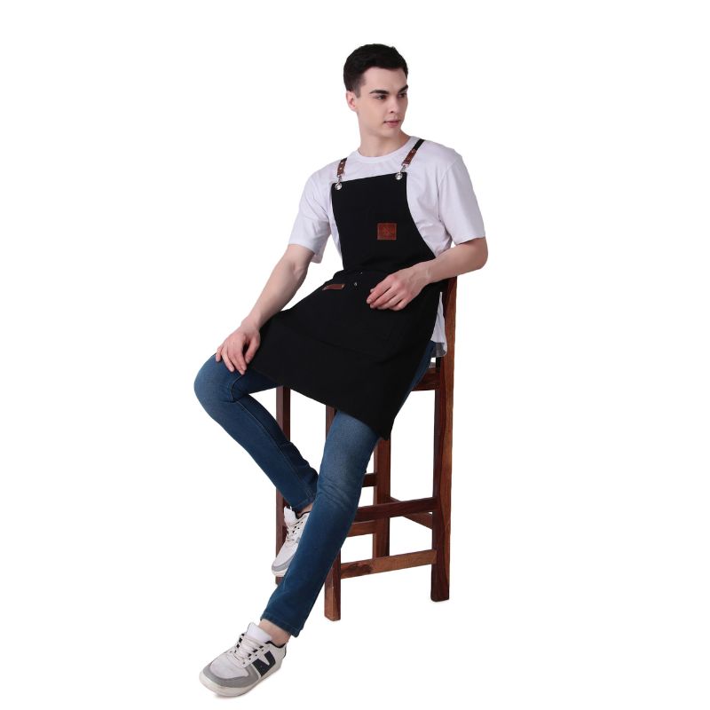 Person wearing a black apron sitting on a wooden stool against a white background