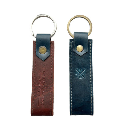 Two leather keychains, one brown and one black, on a white background.