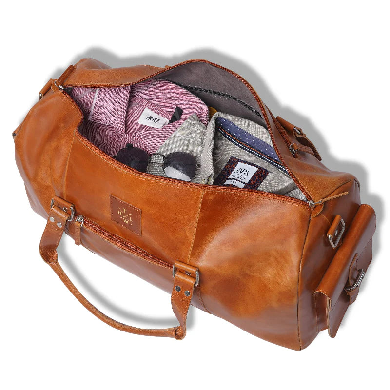 Brown leather duffel bag with clothes inside on a white background