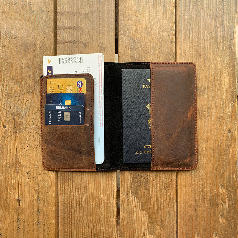 Brown leather wallet with cards and a passport on a wooden surface