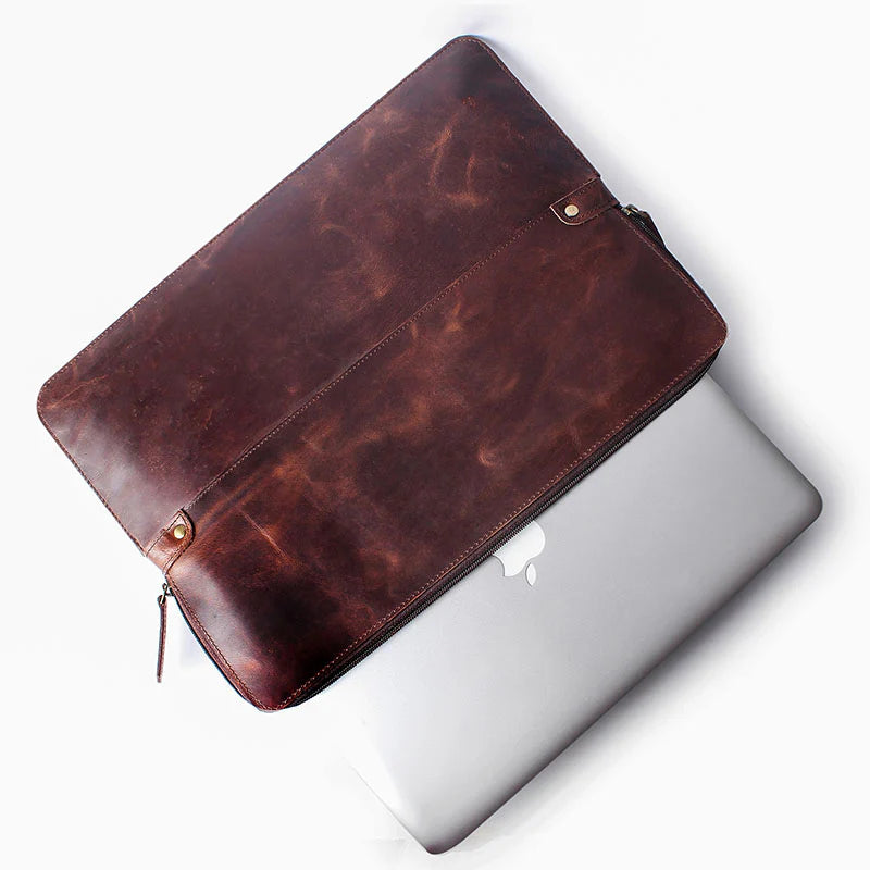 Brown leather laptop sleeve on a silver laptop with a white background