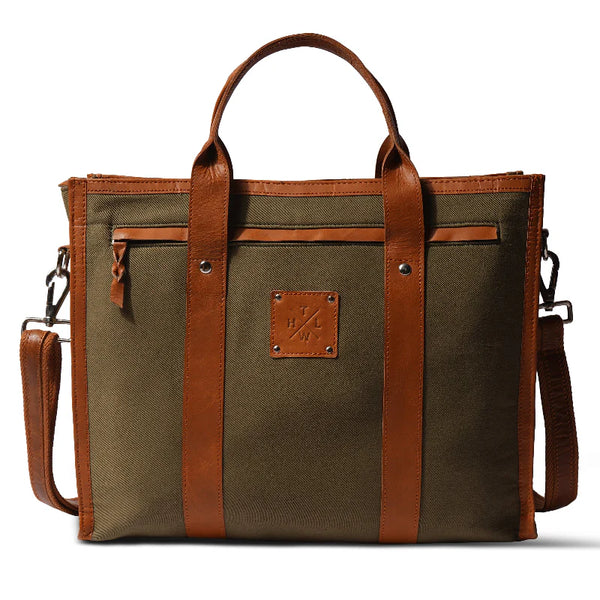 Green canvas bag with brown leather straps and handle on a white background