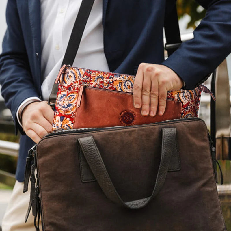 Person holding a brown leather bag with a colorful interior pocket.