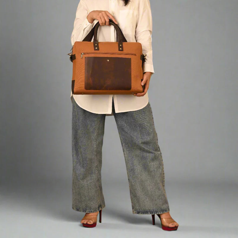 Person holding a brown leather briefcase against a gray background