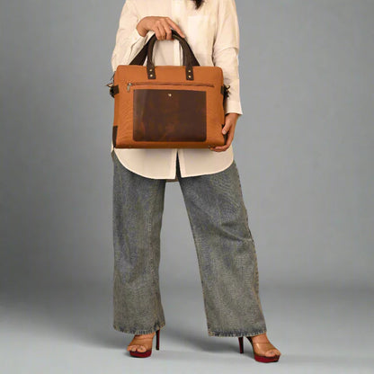 Person holding a brown leather briefcase against a gray background
