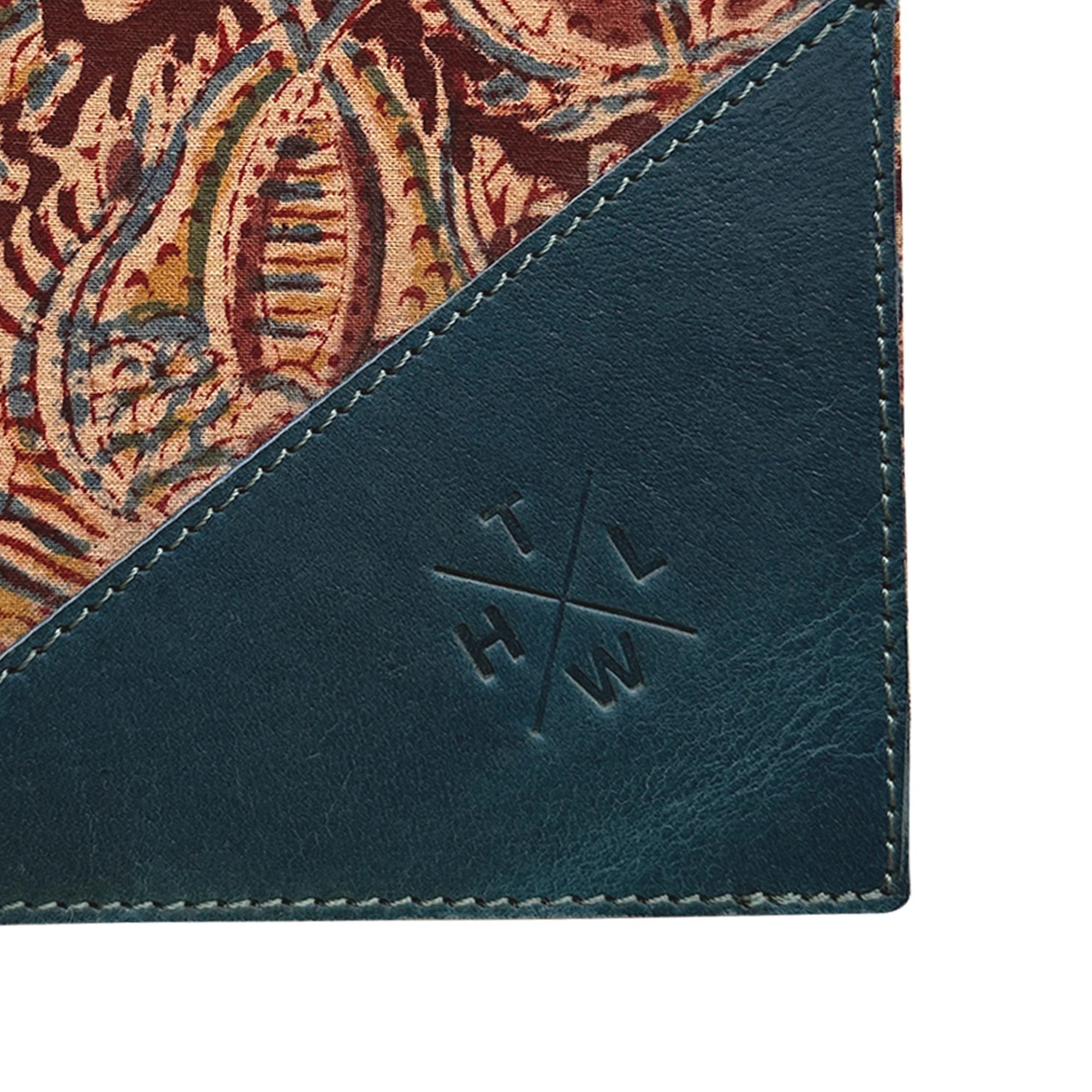 Close-up of a product with a patterned corner and embossed logo on a teal background
