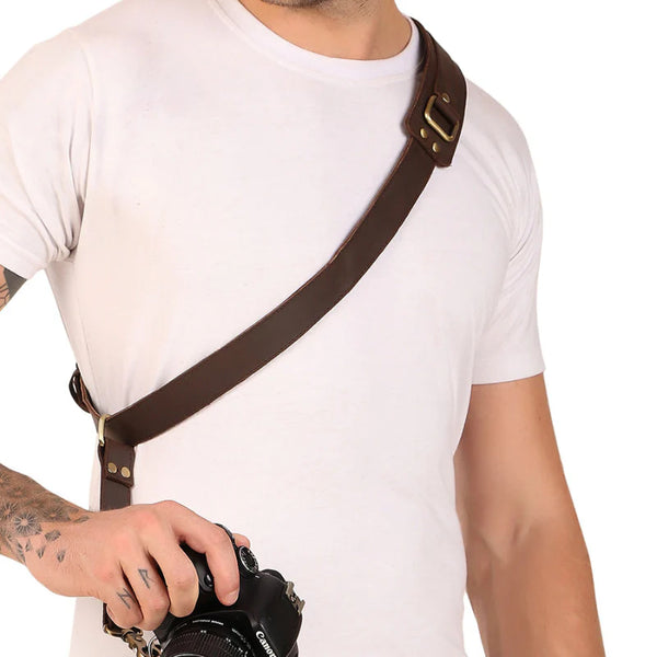 Person wearing a brown leather camera strap over a white shirt