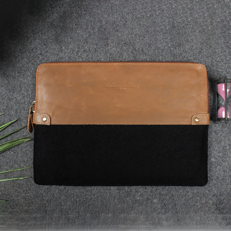 Brown and black leather pouch on a gray surface with a small plant.