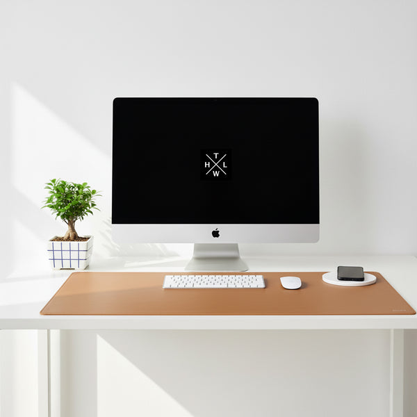 Modern desk setup with a computer monitor, keyboard, mouse, and phone on a wooden desk pad.