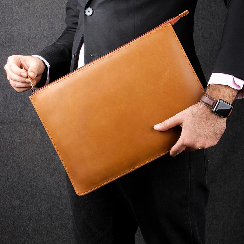 Person holding a brown leather clutch bag against a dark background