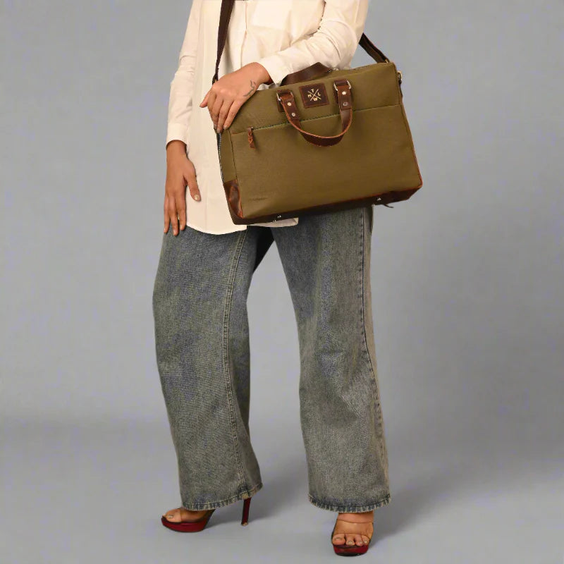 Person holding a green handbag against a gray background