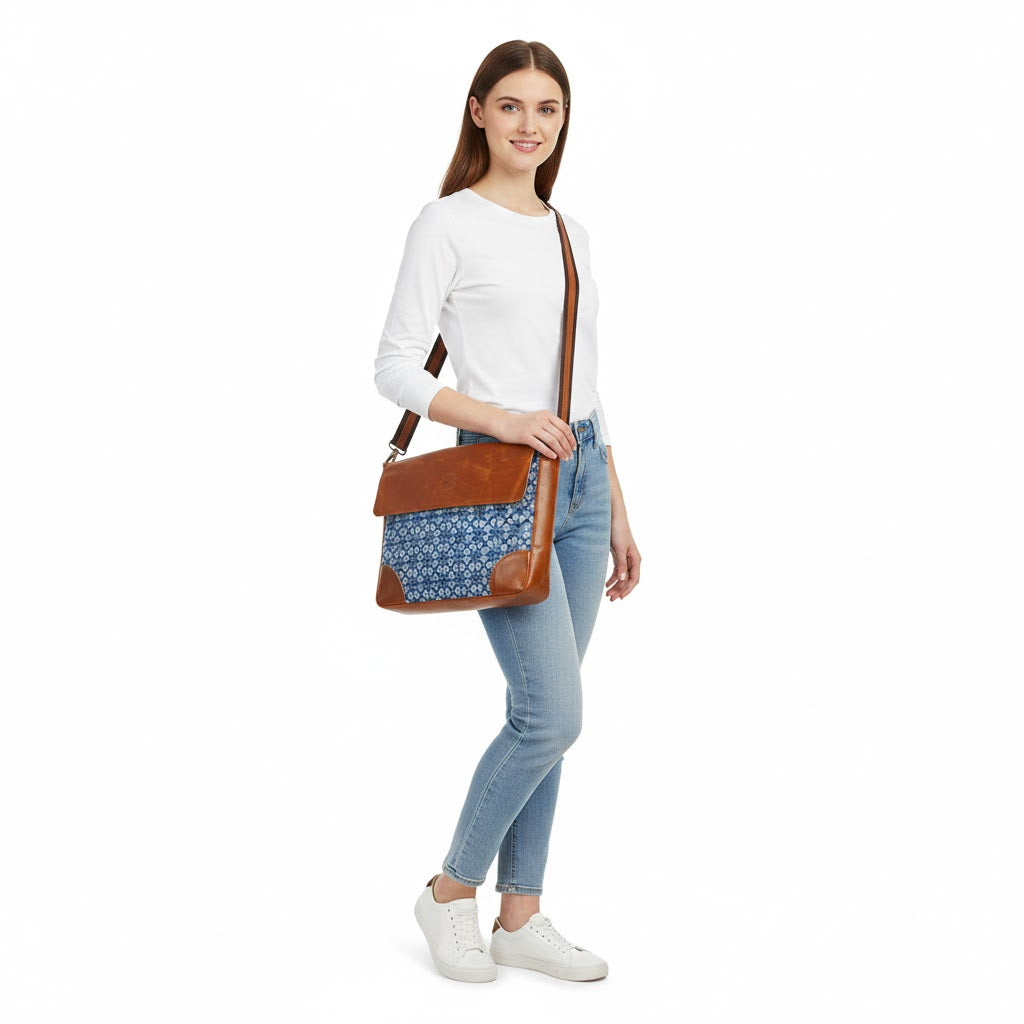 Woman holding a brown crossbody bag with a blue patterned pocket on a white background