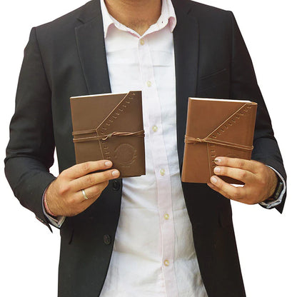 Person holding two brown leather journals against a white background