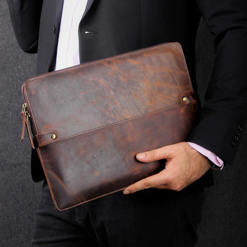 Person holding a brown leather briefcase against a dark background